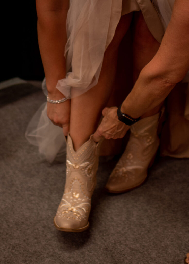 Bride putting on western wedding boots