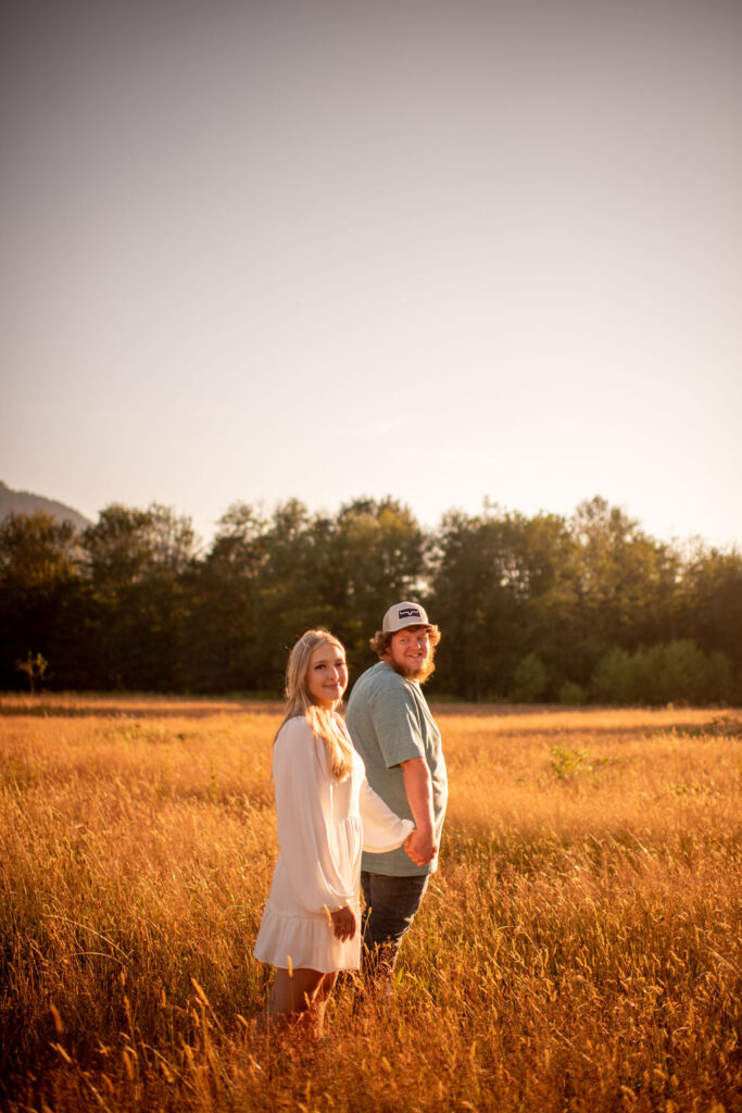Couple posing for golden hour field engagement session in Washington