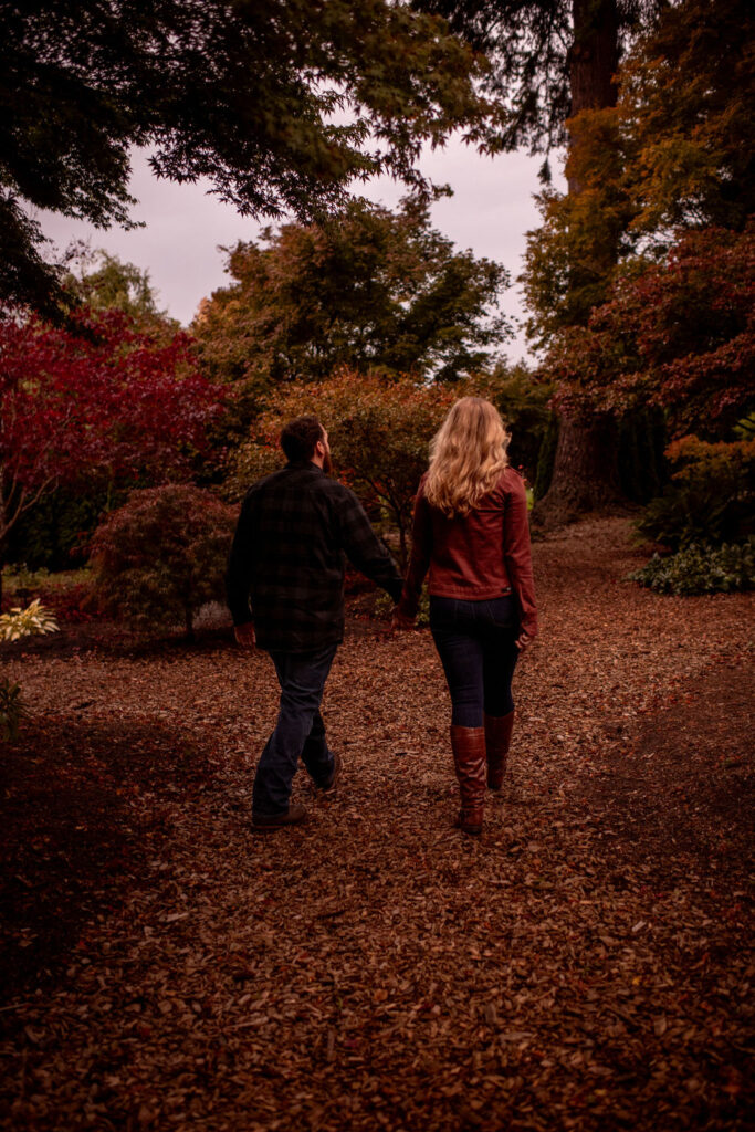 Couple walking holding hands at evergreen arboretum gardens during their fall engagement session