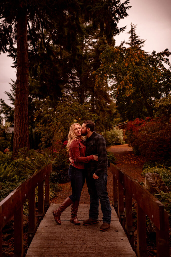couple kissing on the cheek at evergreen arboretum gardens 