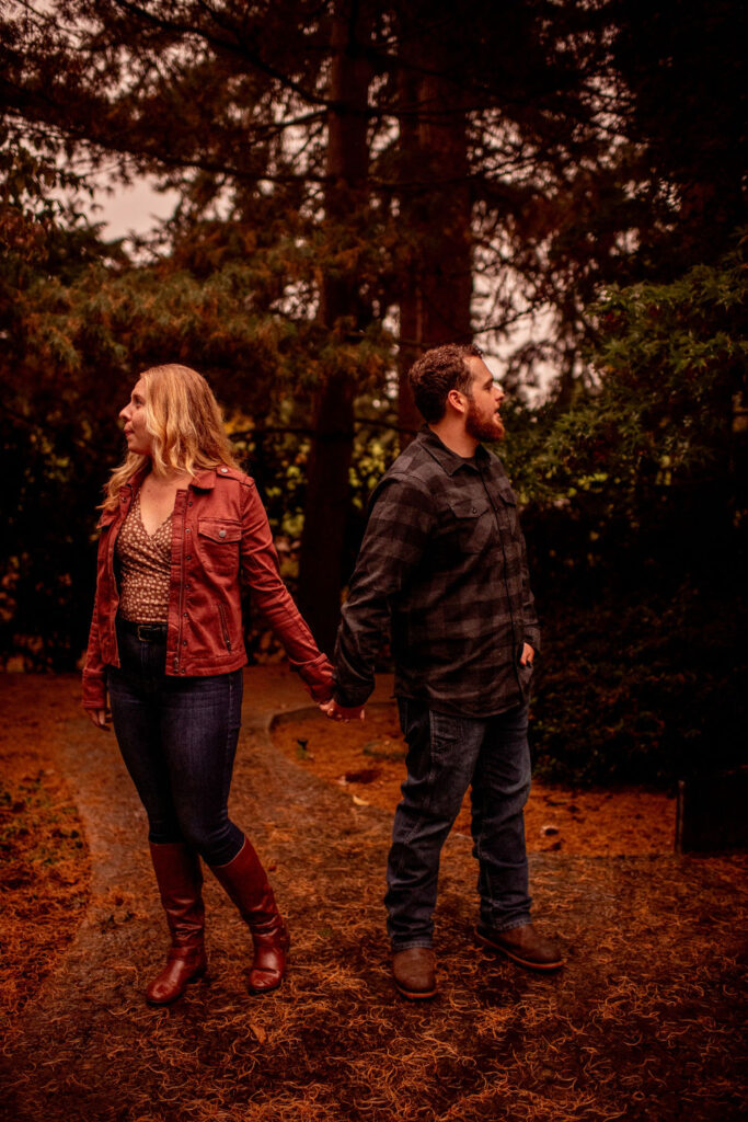 Couple holding hands looking away from each other during their fall engagement photoshoot