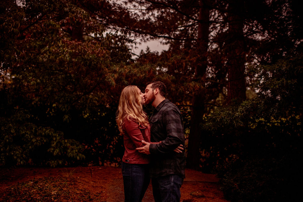 beautiful engaged couple kissing each other at evergreen arboretum gardens 