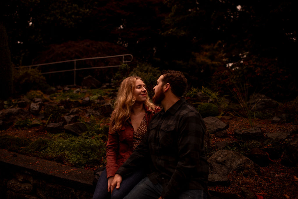Couple seating looking and smiling at each other during their fall engagement photoshoot